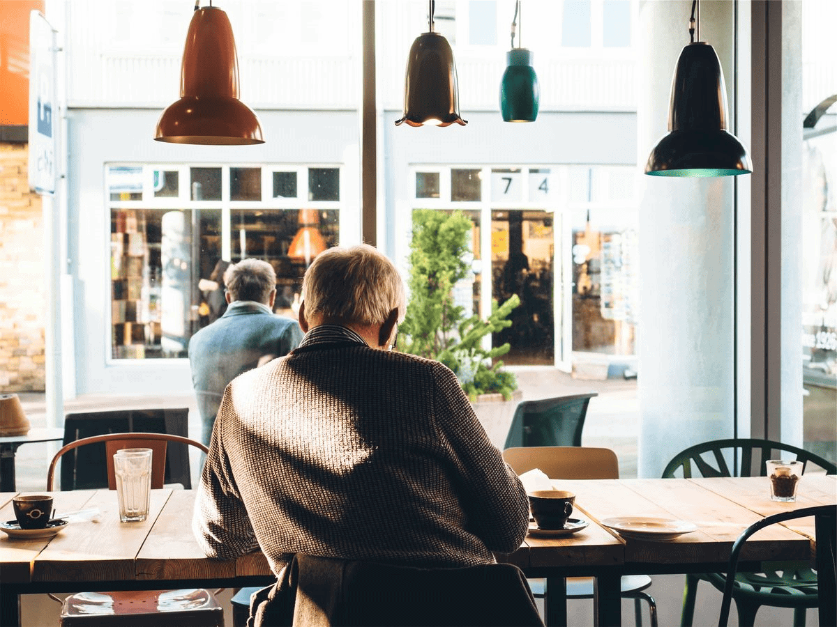 Professional senior man in cafe looking out large windows