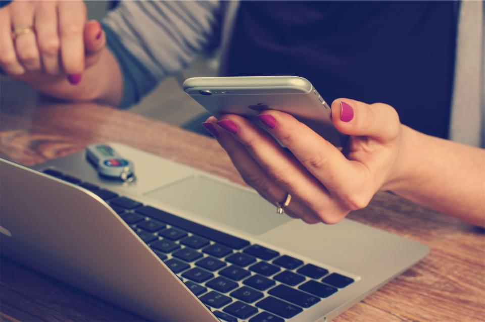 Close-up of polished female hands working across multiple technical devices