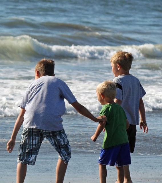 Three children playing in ocean waves