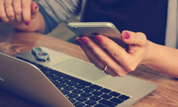 Close-up of polished female hands working across multiple technical devices