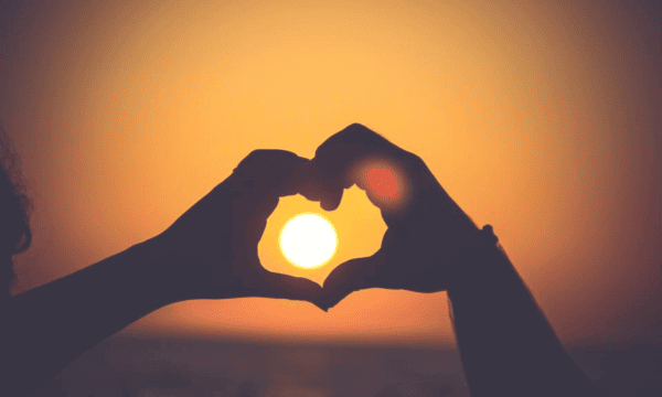 Hands in heart shape around setting sun