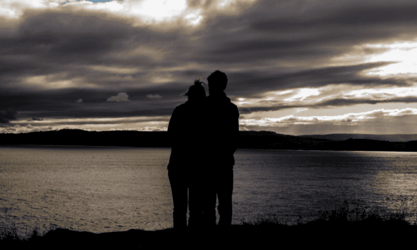 Photo of couple standing at the edge of a lake