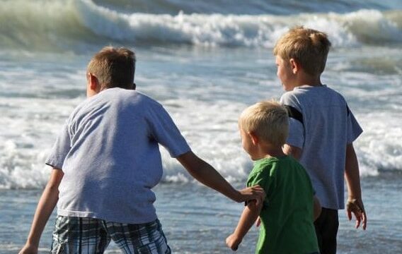 Three children playing in ocean waves