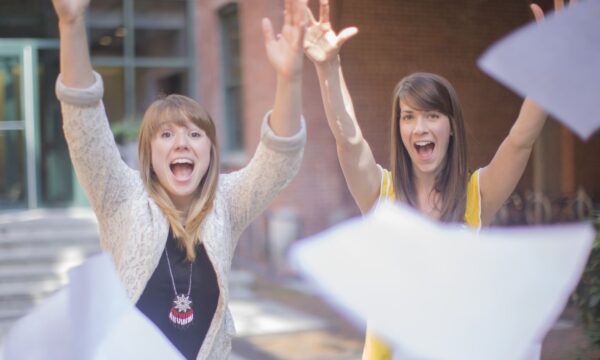 Photo of two young women throwing paper